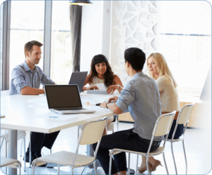 A group of people sitting around a table with laptops.